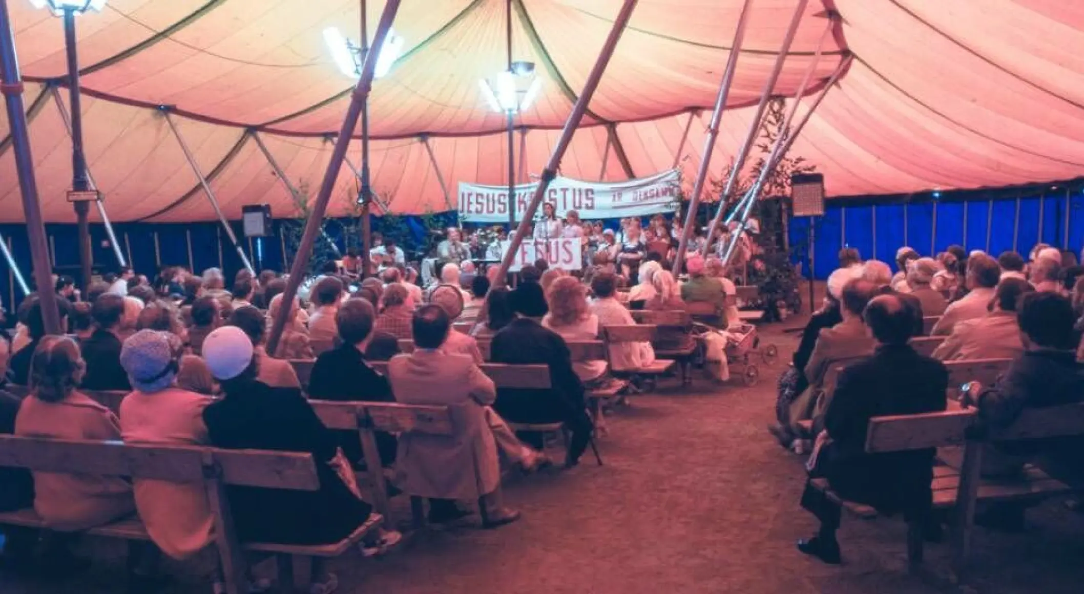 Fullsatt Maranata-möte med människor på scen.